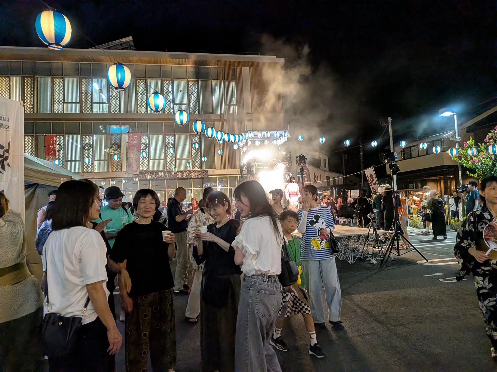 青白い提灯の列と出店の煙が残る、踊りの輪が解けたあとのはんのう昭和盆踊り会場