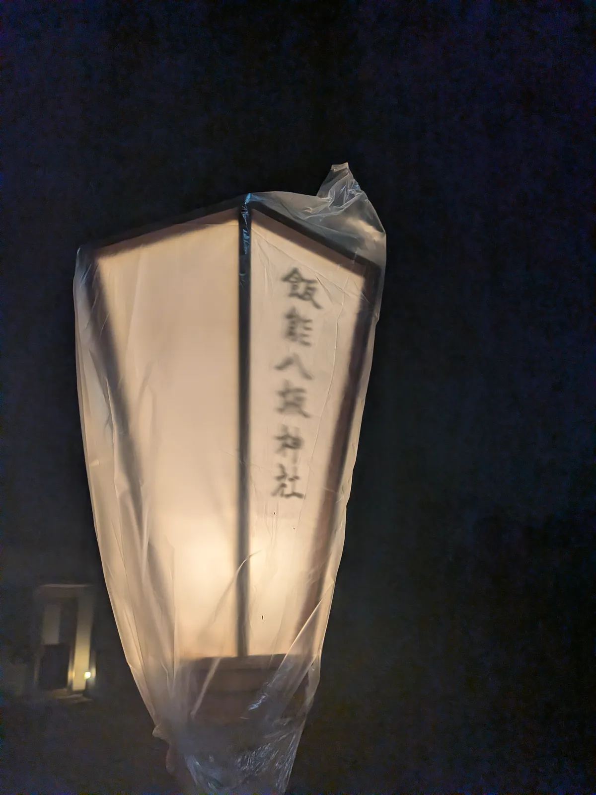 雨除けに包まれて灯る飯能八坂神社の提灯